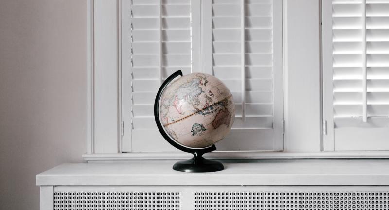 World globe on white bench in front of shutters
