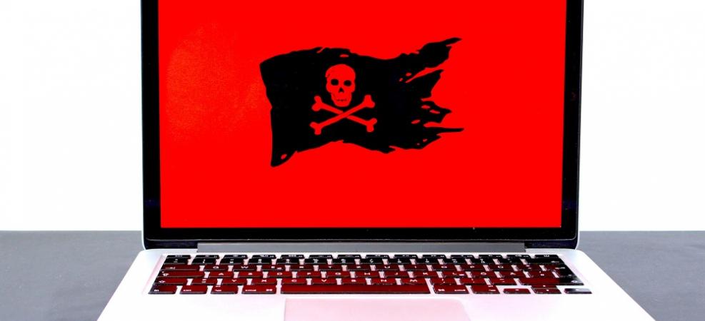 Laptop computer with skull and crossbones on screen, indicating danger