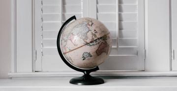 World globe on white bench in front of shutters