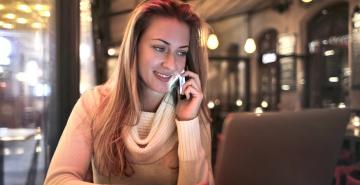 Woman smiling while on phone in a quiet cafe